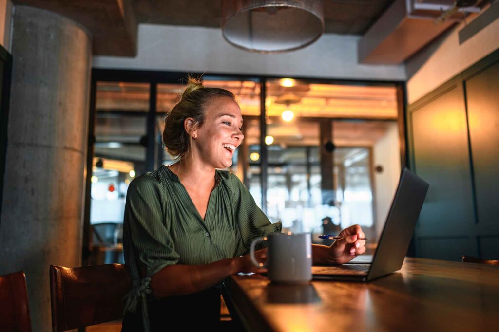 Laughing Young Businesswoman Video Conferencing on Laptop