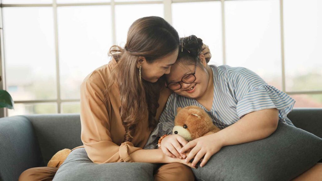 Mother supporting sweet down syndrome daughter