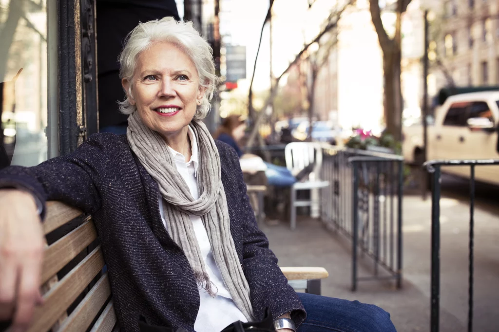 Senior woman sitting on a bench outside.