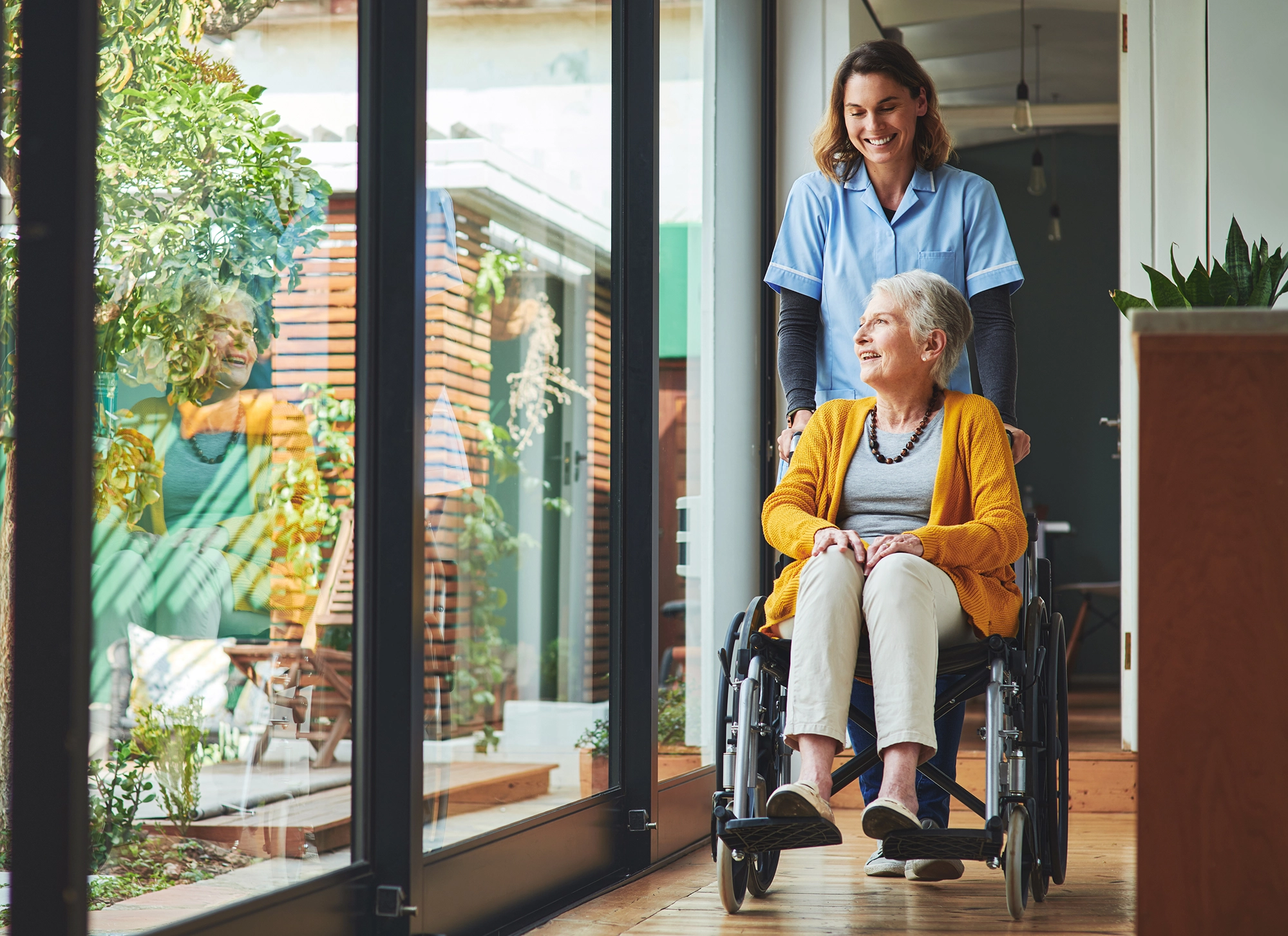 Old woman in a wheel chair getting pushed by a nurse.