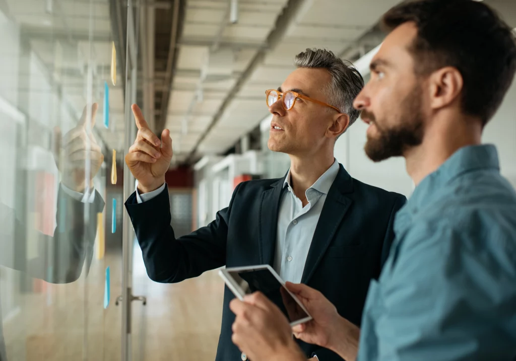 Two men looking at a white board.