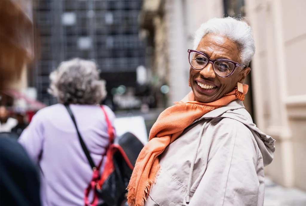 Senior woman in glasses looking over her shoulder.