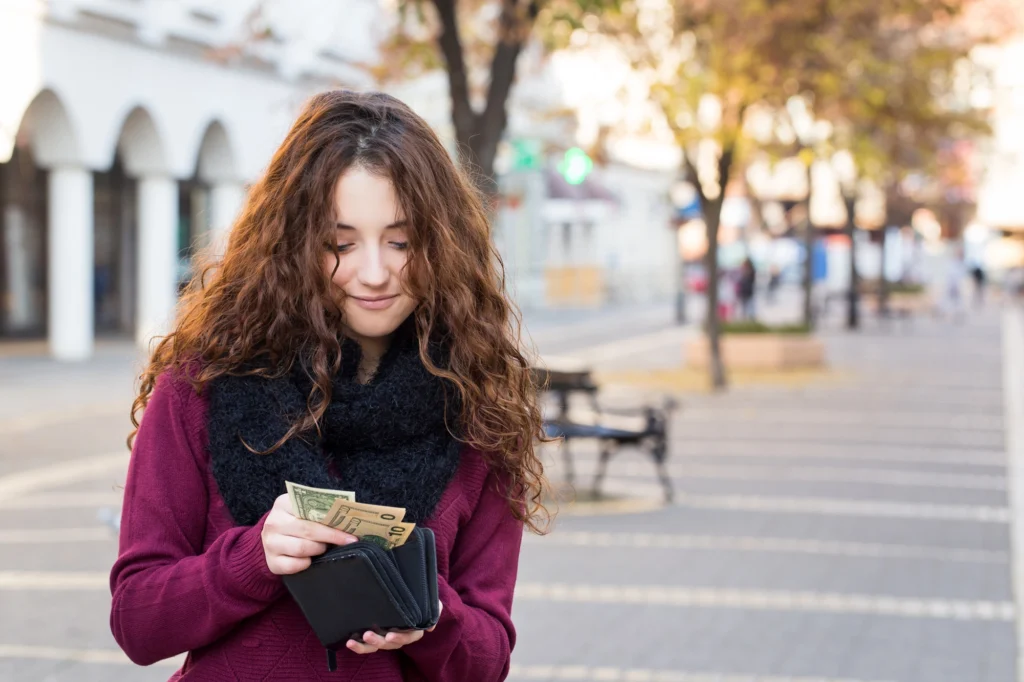 Teenager looking at cash from her wallet