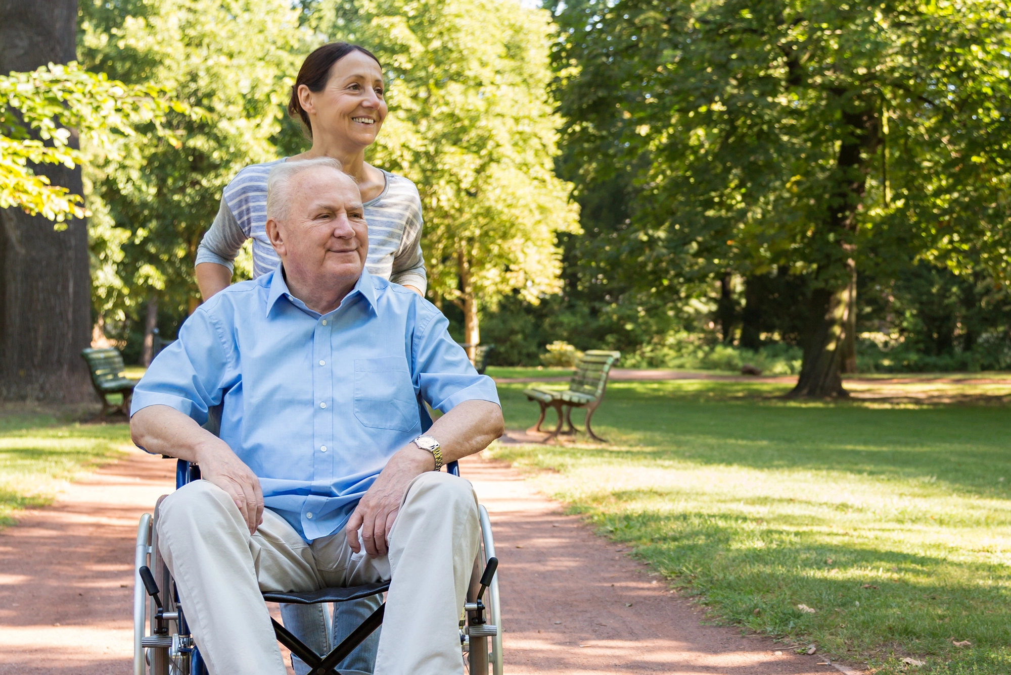 Woman pushing senior man in wheelchair