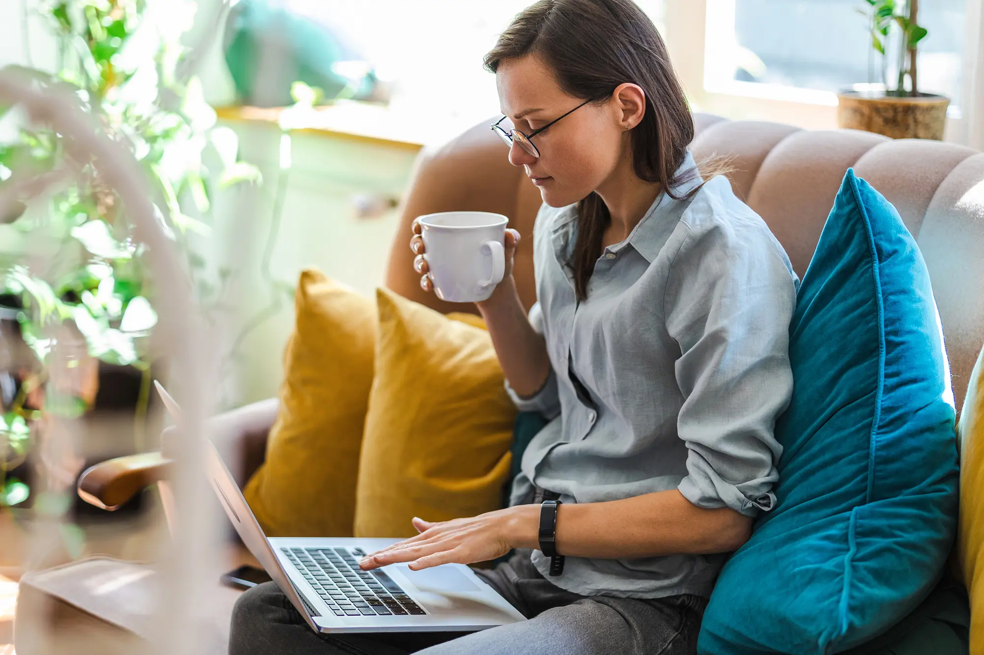Woman sitting on the couch with a coffee and laptop