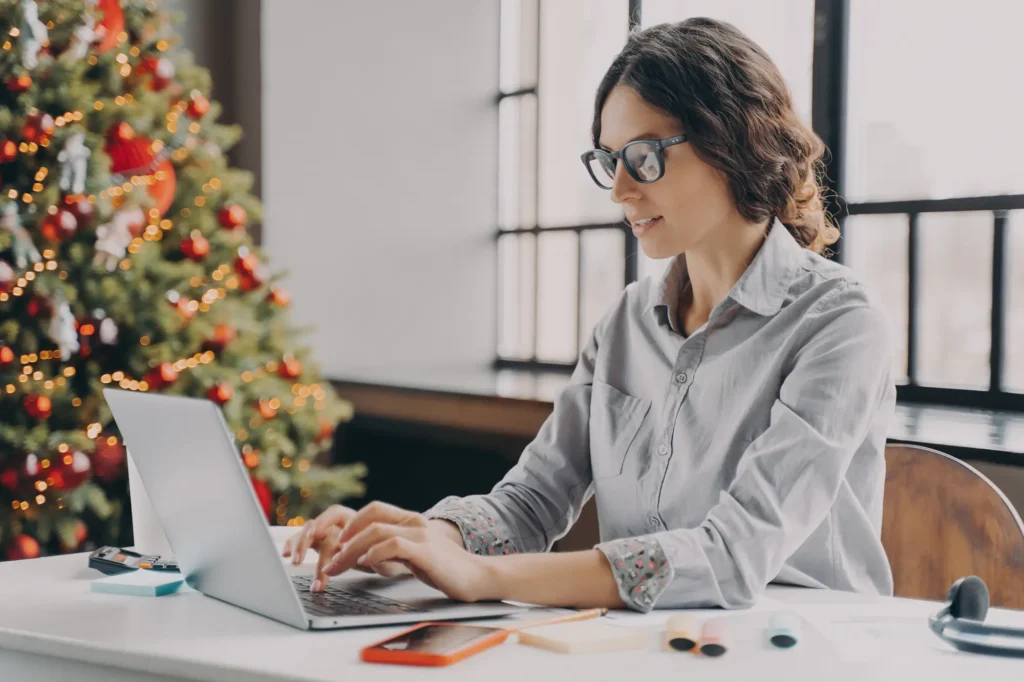 Woman wearing glasses working on a laptop.