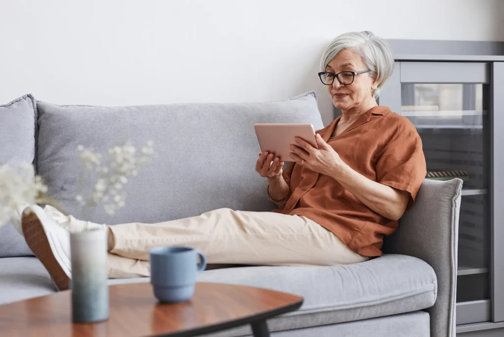 Senior woman on couch looking at her tablet.