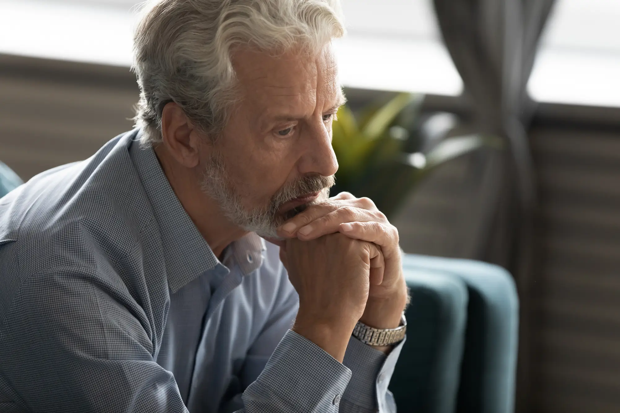 Older man sitting on couch thinking