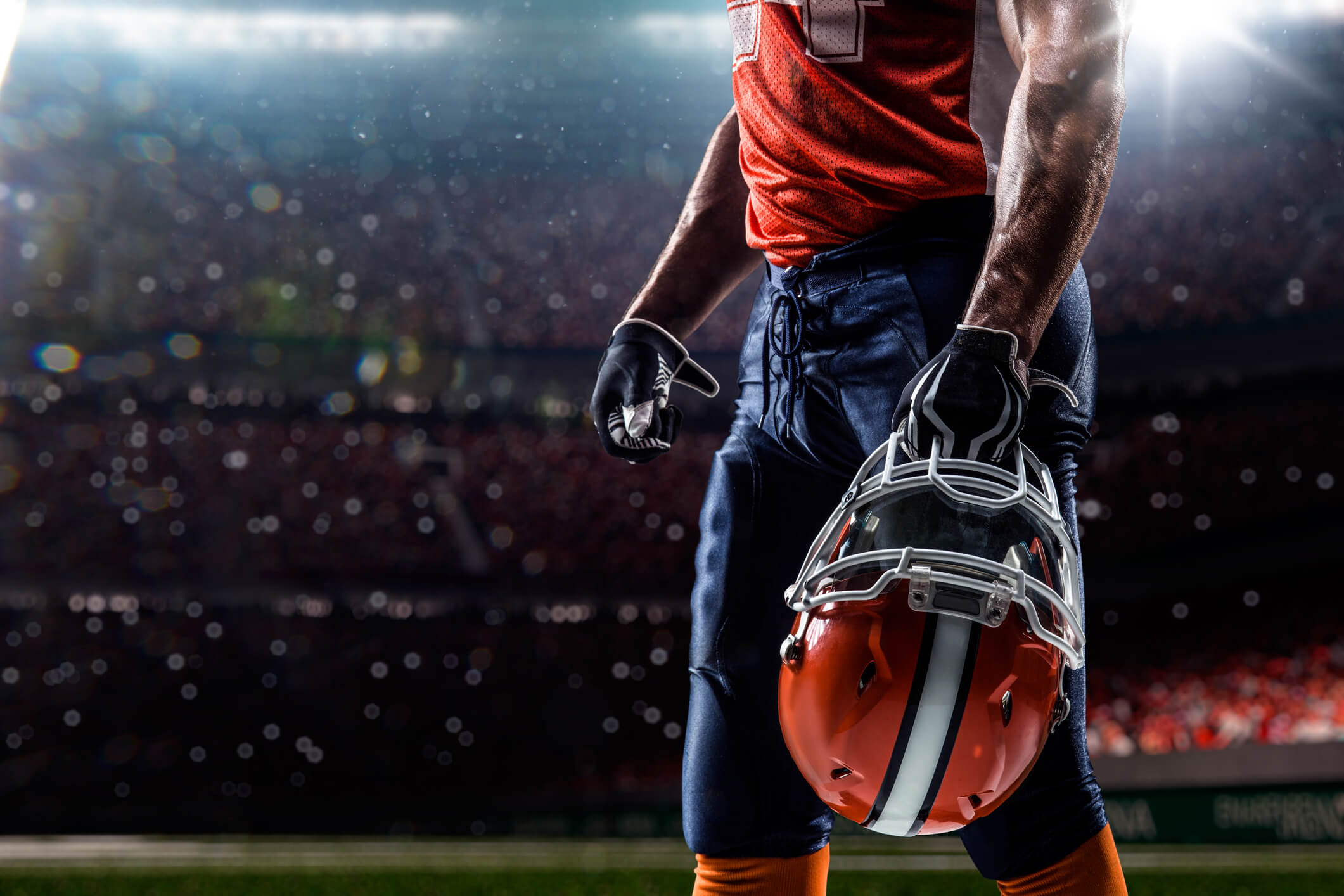professional football player in stadium, carrying his helmet in hand