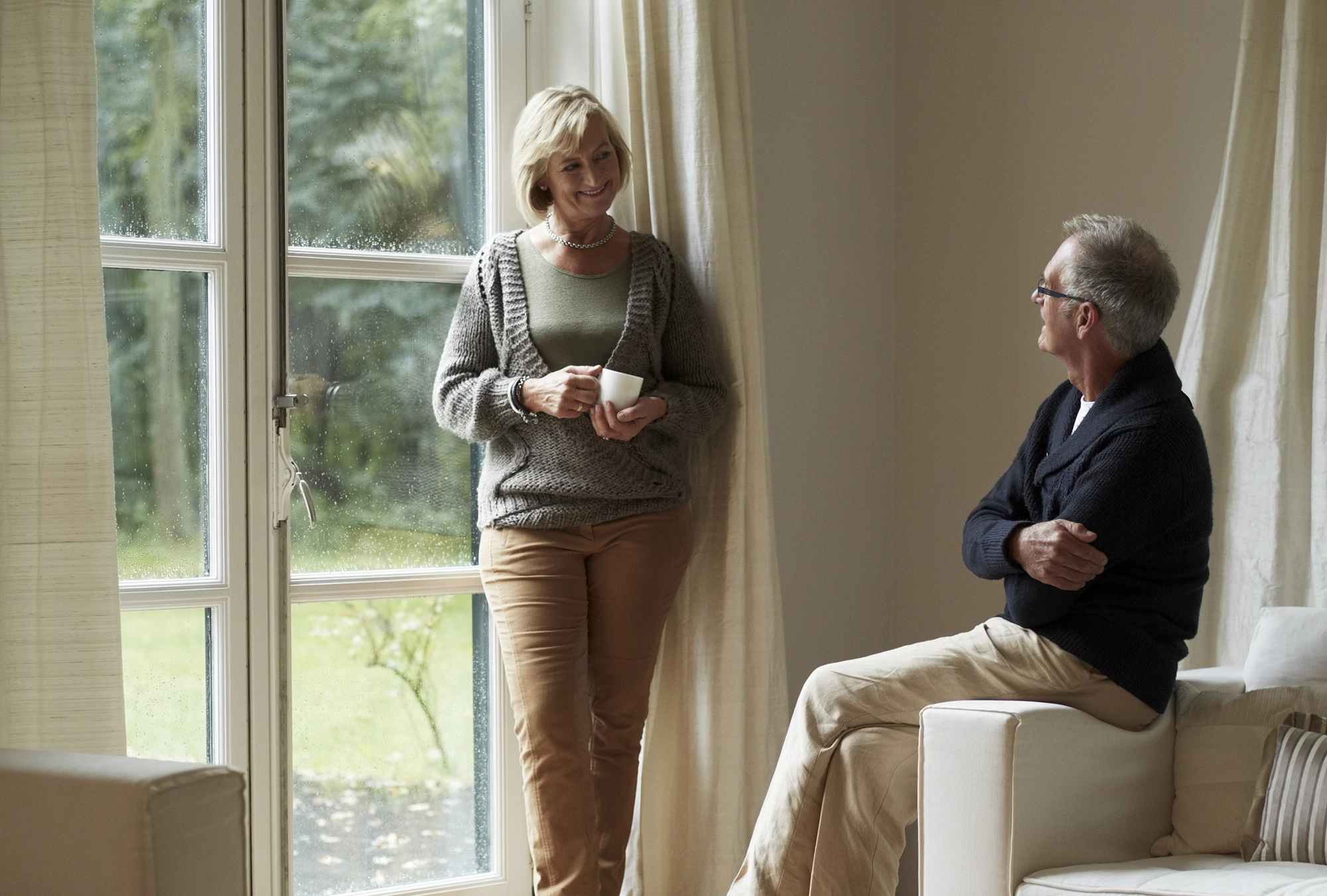 Senior couple having a conversation in the living room by the window