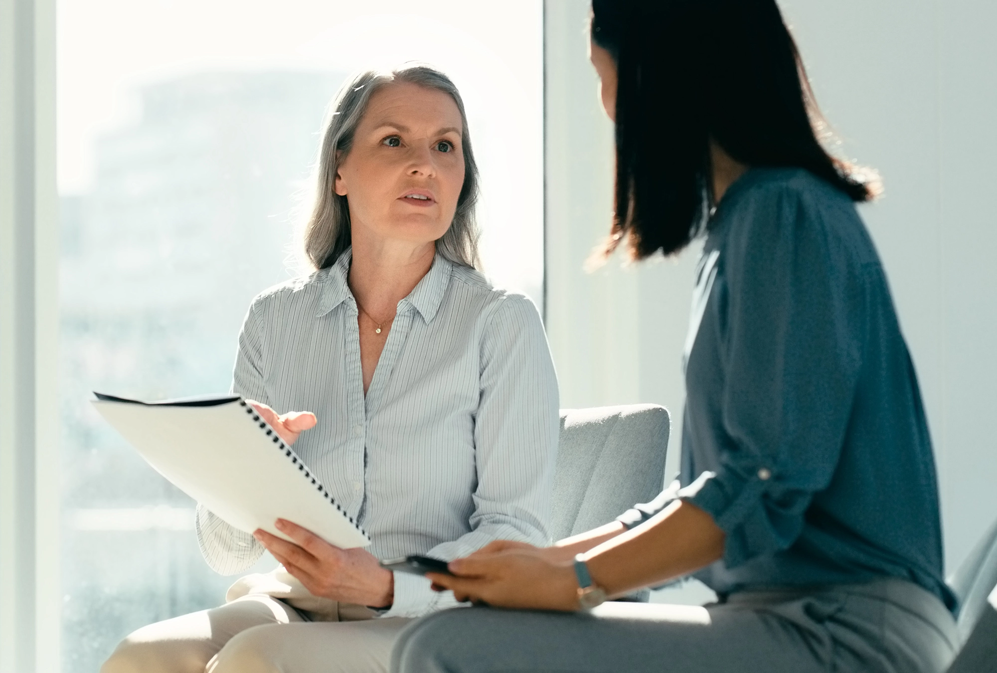 woman holding divorce paperwork while speaking to a financial advisor in office