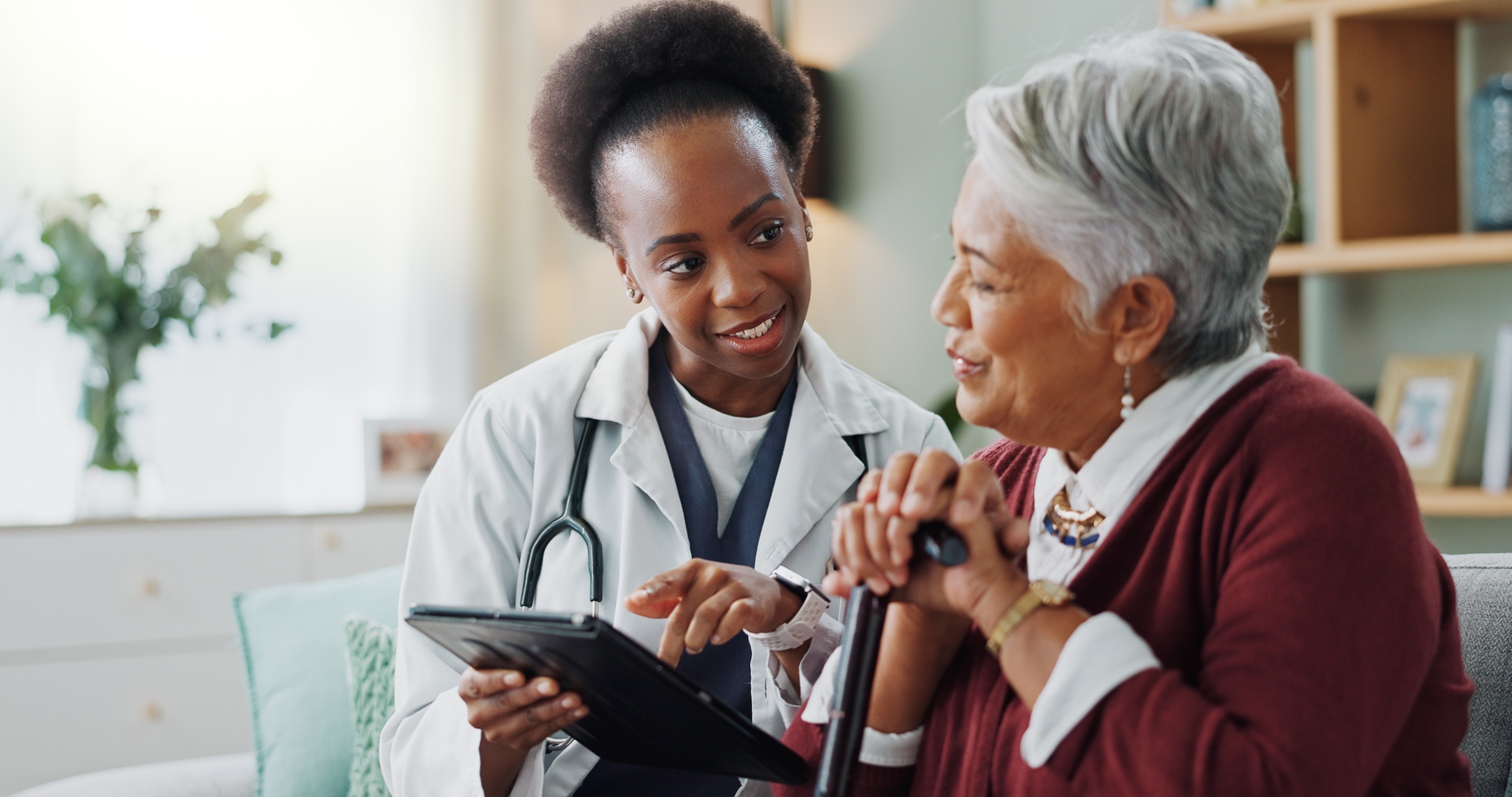 Senior woman and doctor with tablet for consulting with expert advice, explaining medical report or healthcare.