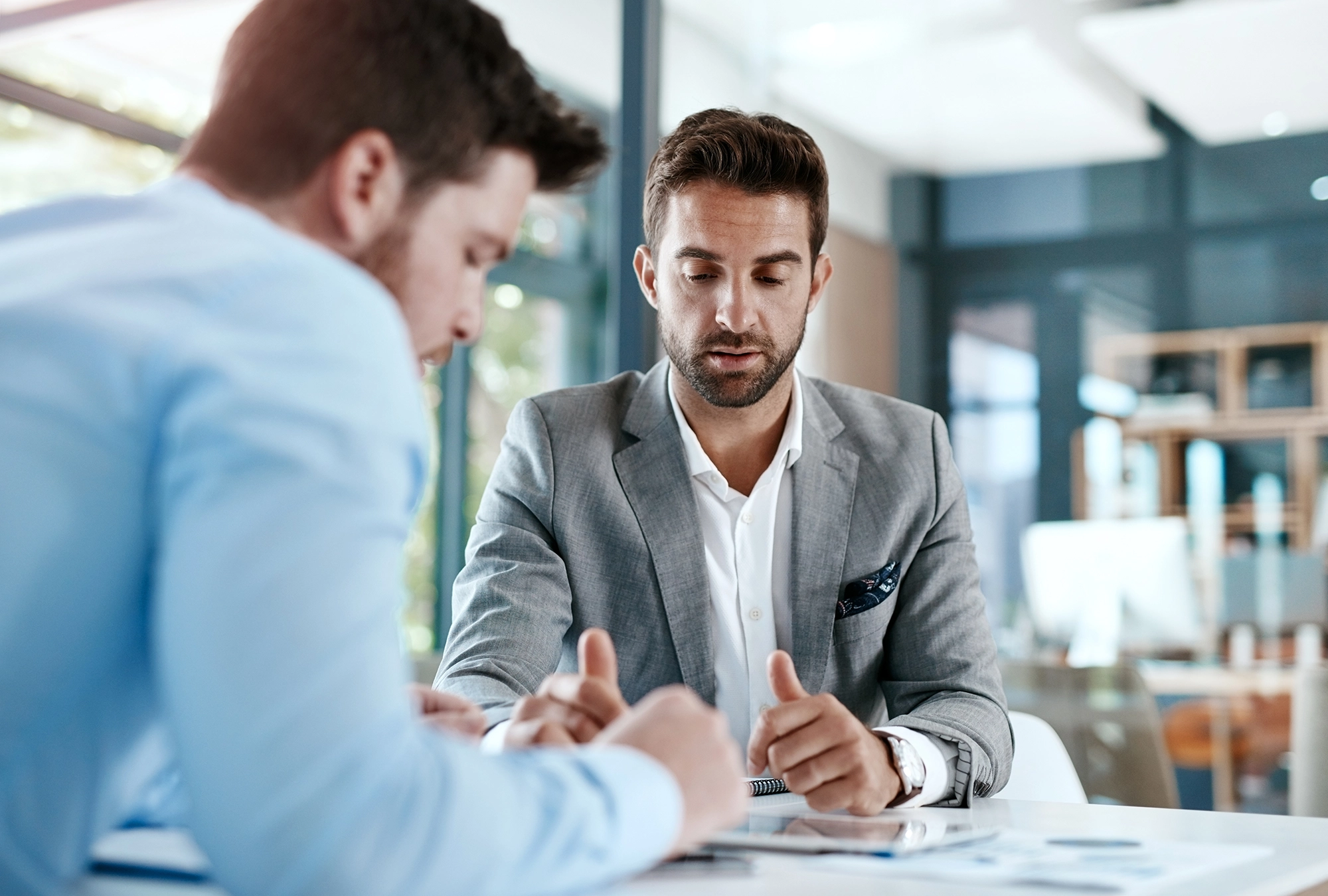 young executive professional sitting with a financial advisor discussing layoff